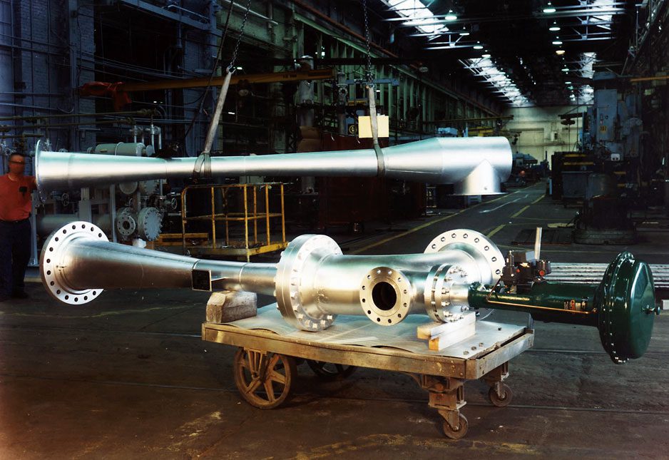 A thermocompressor and a person standing near it, wearing a red shirt and jeans